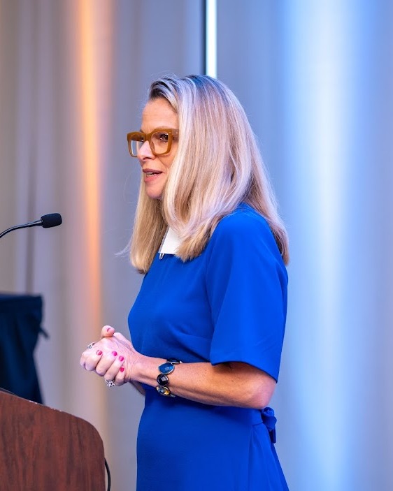 Carrie Blewitt speaking at a podium as spokesperson for clients